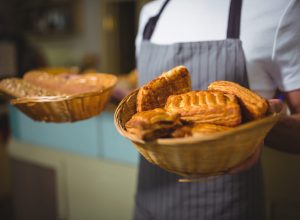 Mid-section of waiter holding a basket of bread in cafÃ©