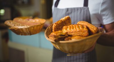 Mid-section of waiter holding a basket of bread in cafÃ©